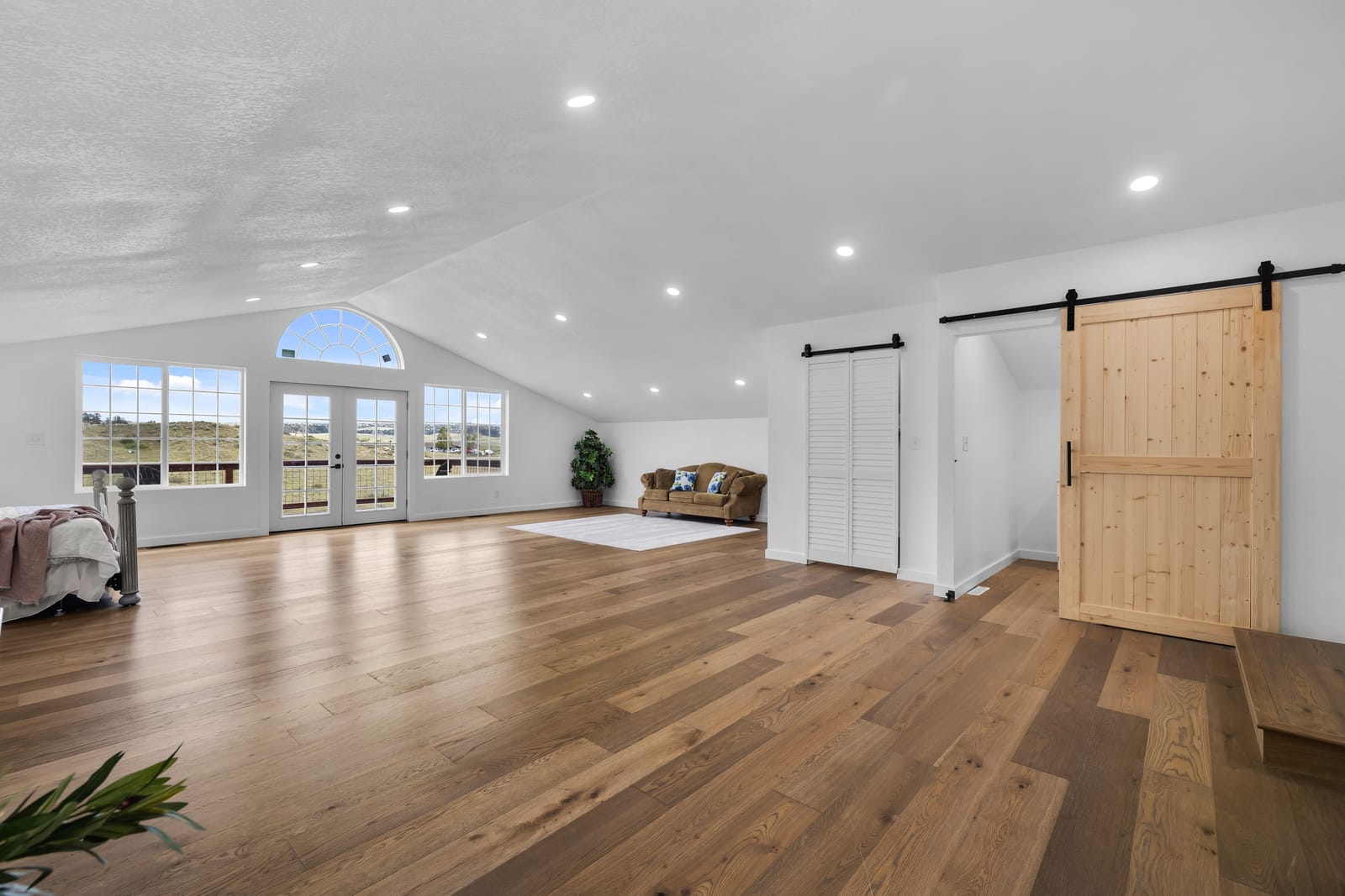 Spacious room with natural light, wood floors, and a sliding barn door used for group and individual therapy at New Frontier Recovery Center in Huntley, Montana